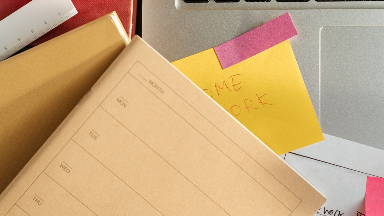 Buku catatan, sticky notes, dan laptop di atas meja